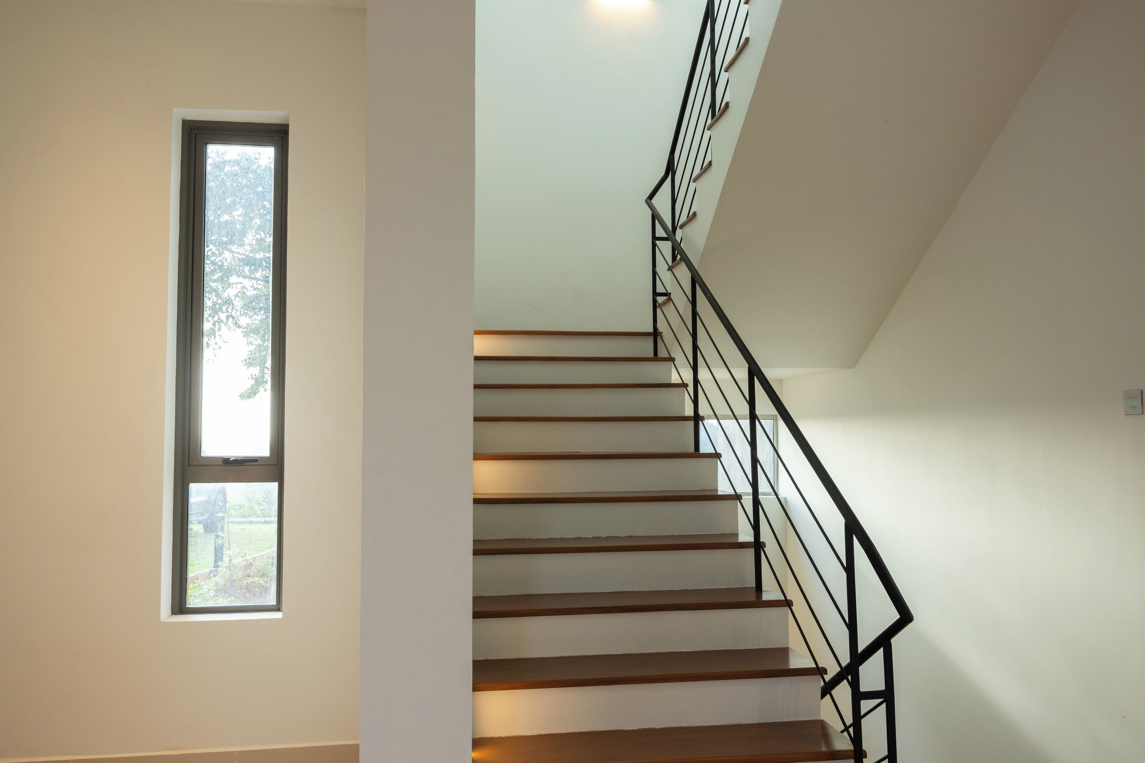 A staircase with wooden steps and black metal railings, leading to an upper floor.