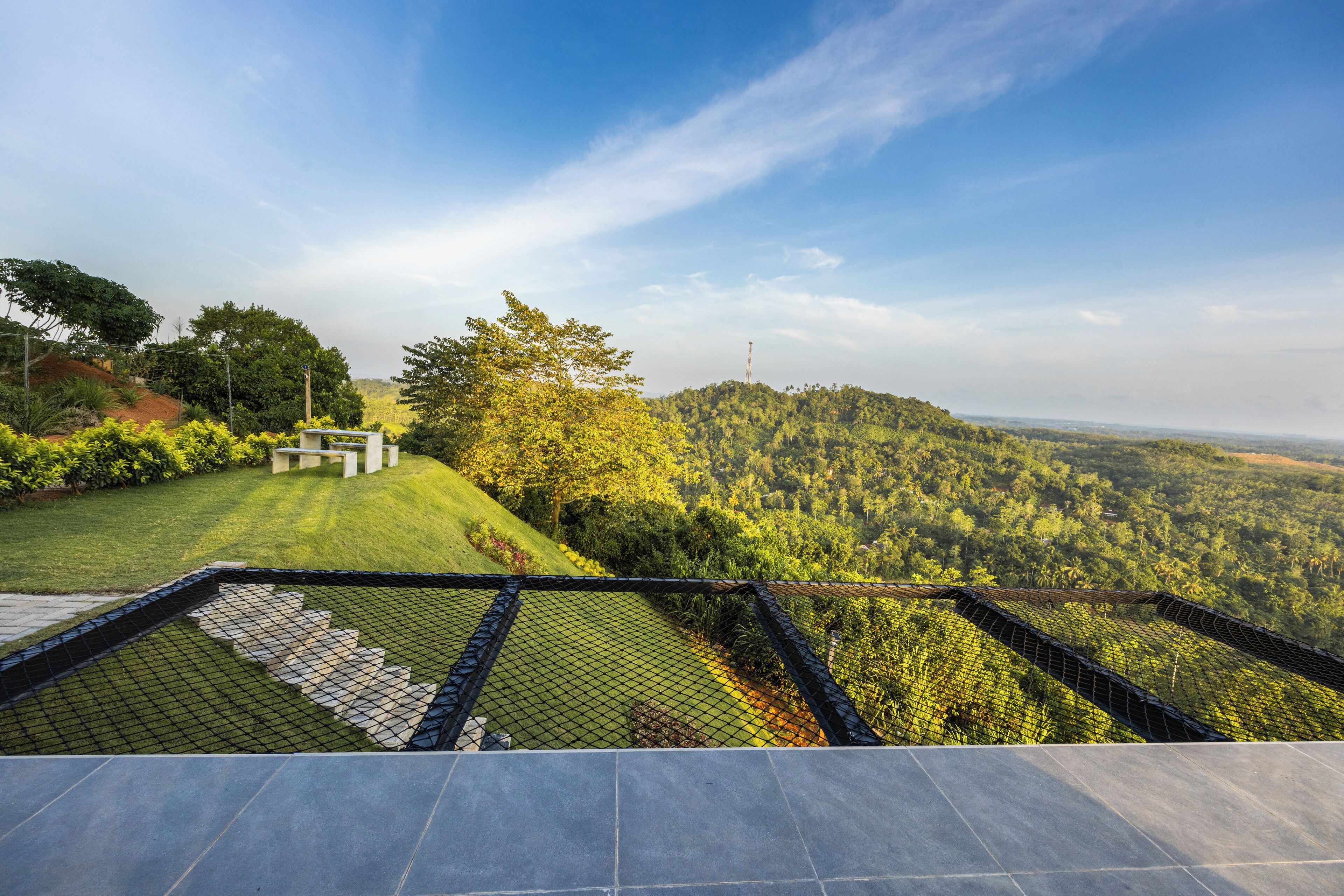 Eine Terrasse mit Blick auf eine üppige, grüne Landschaft und einen entfernten Turm.
