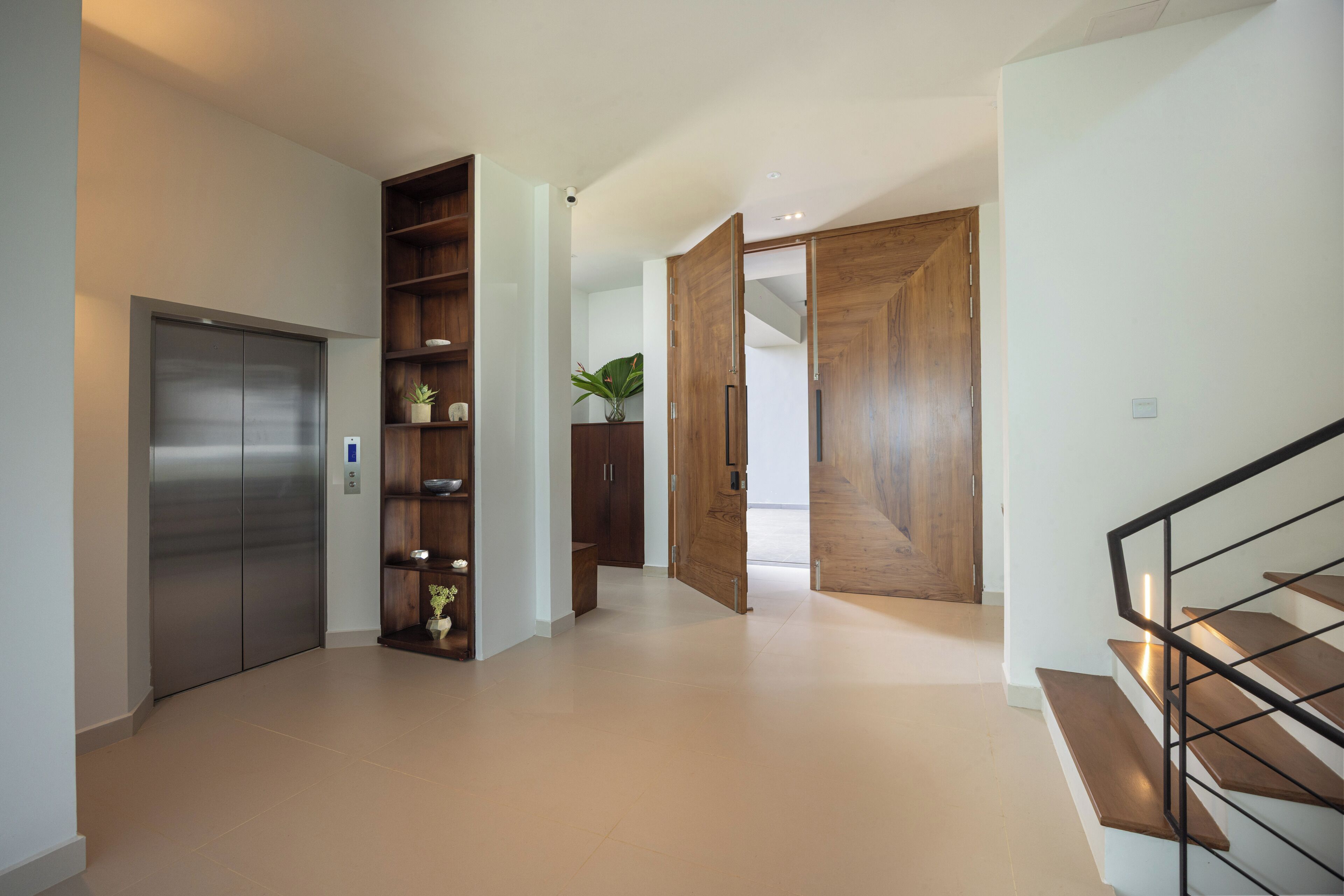Un intérieur moderne avec un escalier, une porte en bois et un ascenseur en métal.