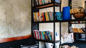Un coin lecture accueillant, avec une bibliothèque remplie de livres, un espace salon confortable agrémenté de coussins à rayures et une petite table préparée pour les repas.
