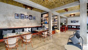 Un vaste espace dédié à la salle à manger, doté de hauts plafonds, de murs en briques apparentes et d’une variété de sièges, notamment des tables et des chaises.