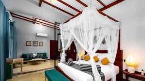 Une chambre à coucher avec un lit à baldaquin, un canapé vert, un banc en bois et une table de chevet avec une lampe.