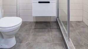 A modern bathroom with a toilet, a sink with a mirror above, and a glass-enclosed shower. - MaRKoS Flat 202 in Loft 2, floor 2, New Gudauri (Gudauri,)