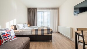 A modern hotel room with a large bed, a sofa, a dining table, and a TV mounted on the wall. - MaRKoS Flat 202 in Loft 2, floor 2, New Gudauri (Gudauri,)