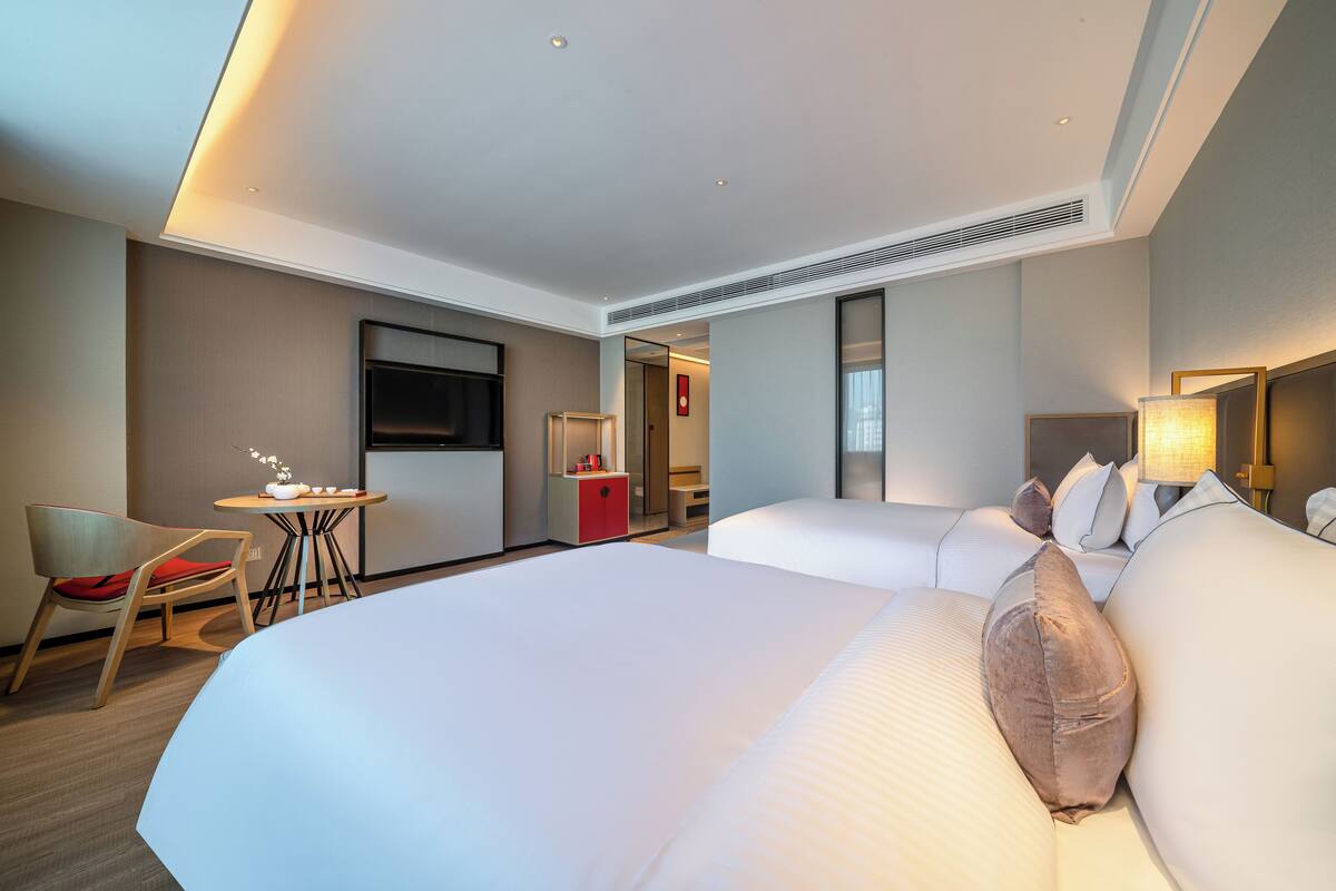 Ein modernes Hotelzimmer mit einem großen Bett, einem Schreibtisch und einem Fernseher.