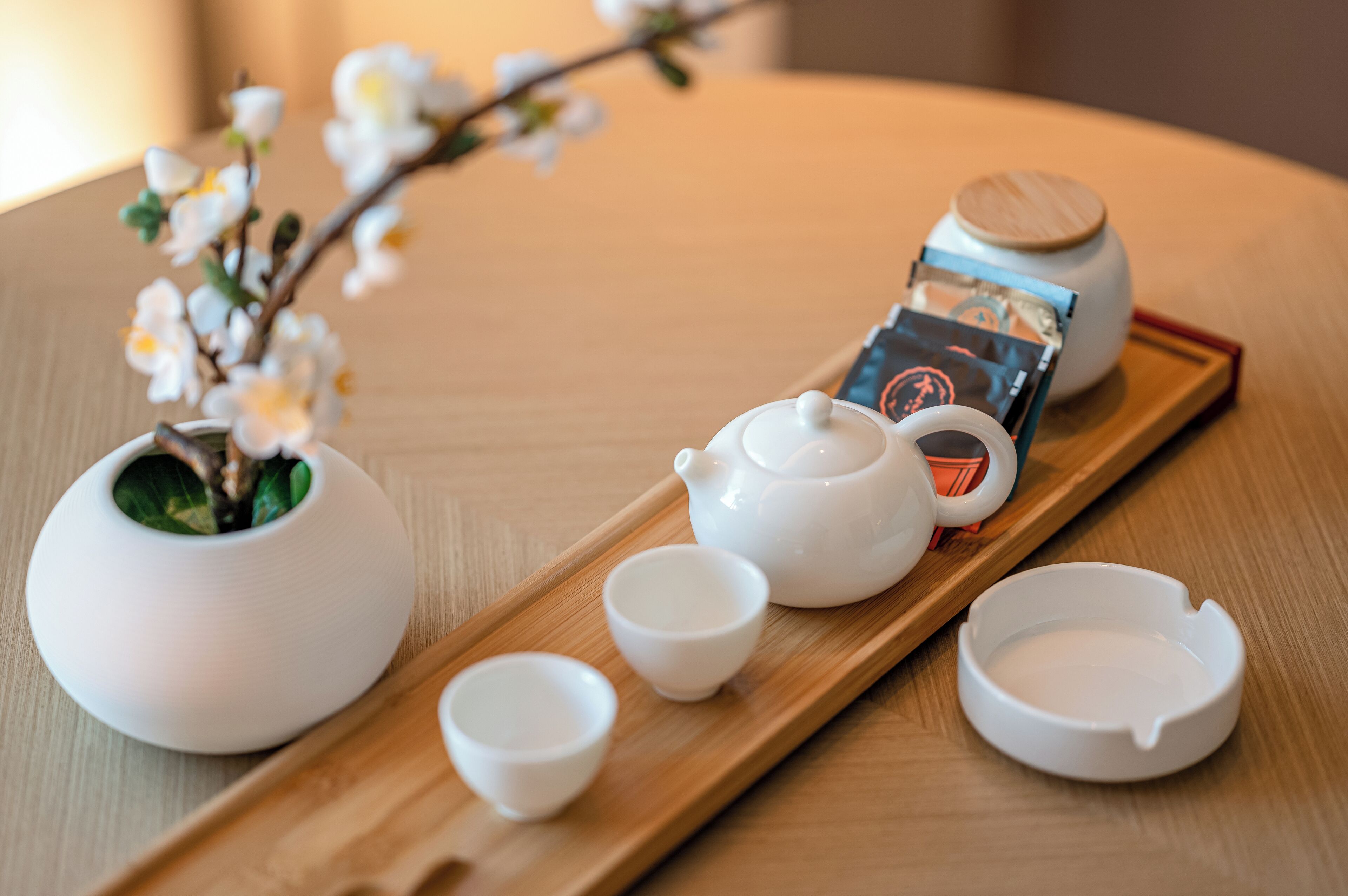 A tray with a teapot, cups, and a tea bag on a wooden table.