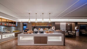 A modern cafe with a central counter, wooden flooring, and pendant lighting. - Yicheng Hotel Wuzhou City Government  (Wuzhou)