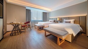 A modern hotel room with a large bed, two bedside tables, a desk with a chair, and a large window with curtains. - Yicheng Hotel Wuzhou City Government  (Wuzhou)