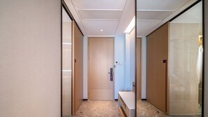 A hallway with a wooden door, a bench, and a wall with a textured pattern. - Yicheng Hotel Wuzhou City Government  (Wuzhou)