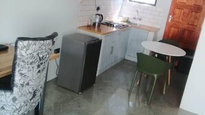 Cozinha compacta com micro-ondas, pia e pequena área de refeições com mesa e cadeiras.