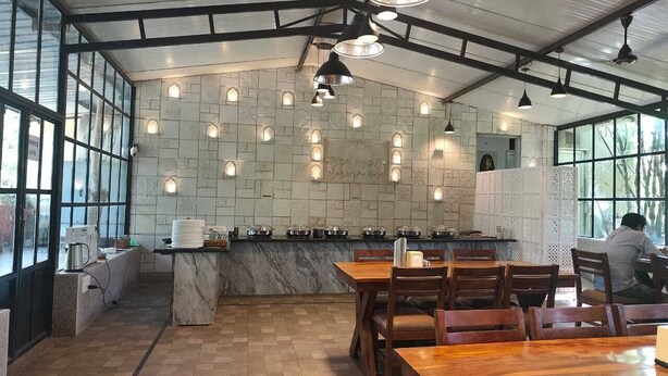A restaurant with a marble counter, wooden tables, and a tiled wall with recessed lighting. - Kanota Camp Resort (Jaipur)