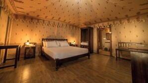A bedroom with a large bed, a wooden desk, a nightstand, and a mirror. - Kanota Camp Resort (Jaipur)