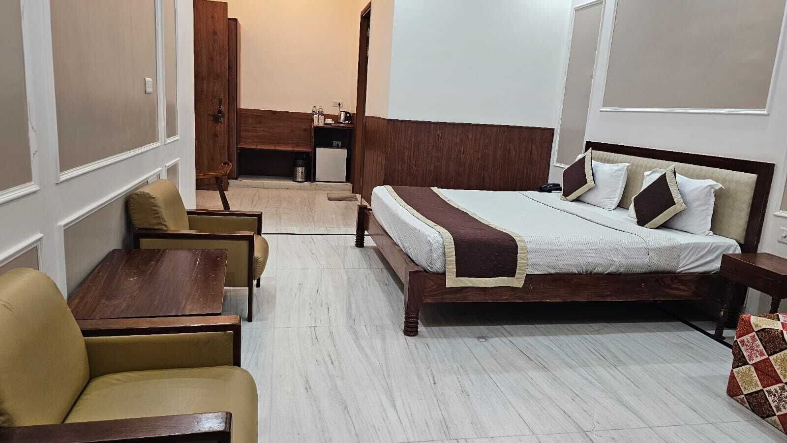 Een hotelkamer met een bed, een tafeltje, twee stoelen, een bureau en een kitchenette.