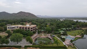 A hotel with a central courtyard, a swimming pool, and a view of surrounding hills. - Kanota Camp Resort (Jaipur)