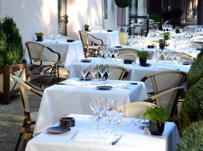 A restaurant with multiple tables set for dining, each with white tablecloths, chairs, and glassware. - LOGIS HOTEL LE PARC DE GEOFFROY (Thiers)