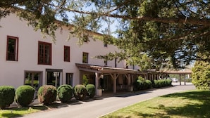 A building with a covered porch, a paved driveway, and neatly trimmed hedges. - LOGIS HOTEL LE PARC DE GEOFFROY (Thiers)