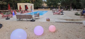 A poolside area with lounge chairs, a small building, and a fountain. - LOGIS HOTEL LE PARC DE GEOFFROY (Thiers)