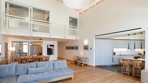 Een ruime woonkamer met een bank, eettafel en stoelen, een keuken met moderne apparatuur, en een balkon met een hekwerk.