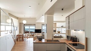 Een moderne keuken met een groot kookeiland, inbouwapparatuur en uitzicht naar buiten.