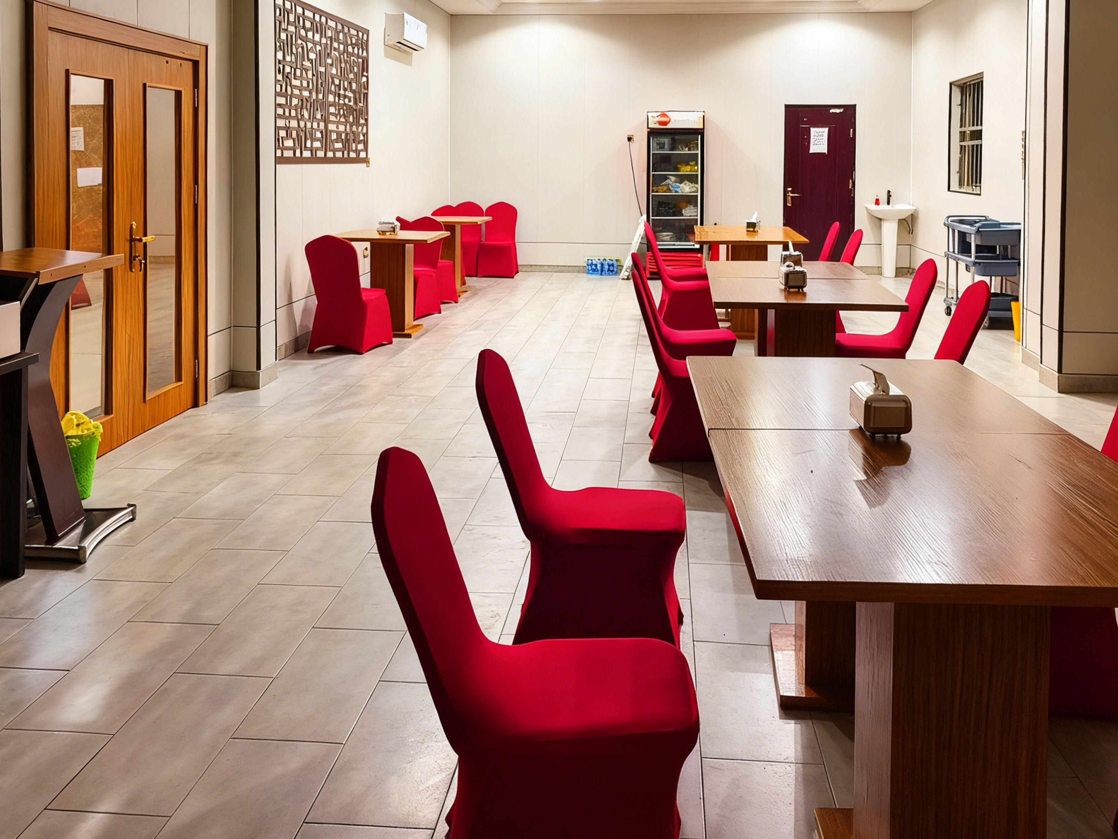 A conference room with red chairs and a long wooden table, equipped with a projector and a whiteboard.