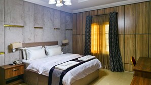 Ein modernes Hotelzimmer mit einem großen Bett, Nachttischen, einem Telefon und einer Lampe.