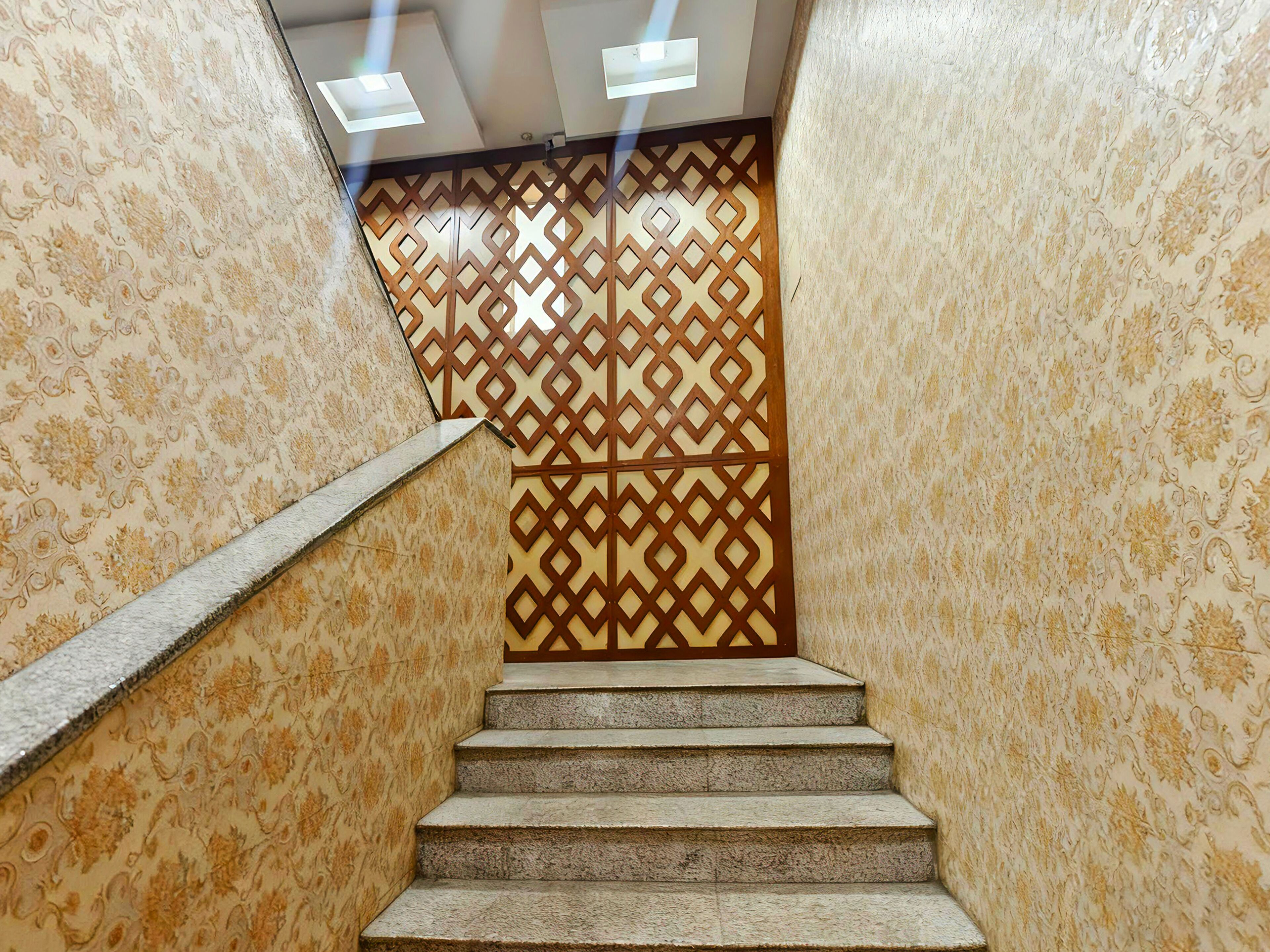 A staircase with patterned wallpaper and a geometric decorative panel.