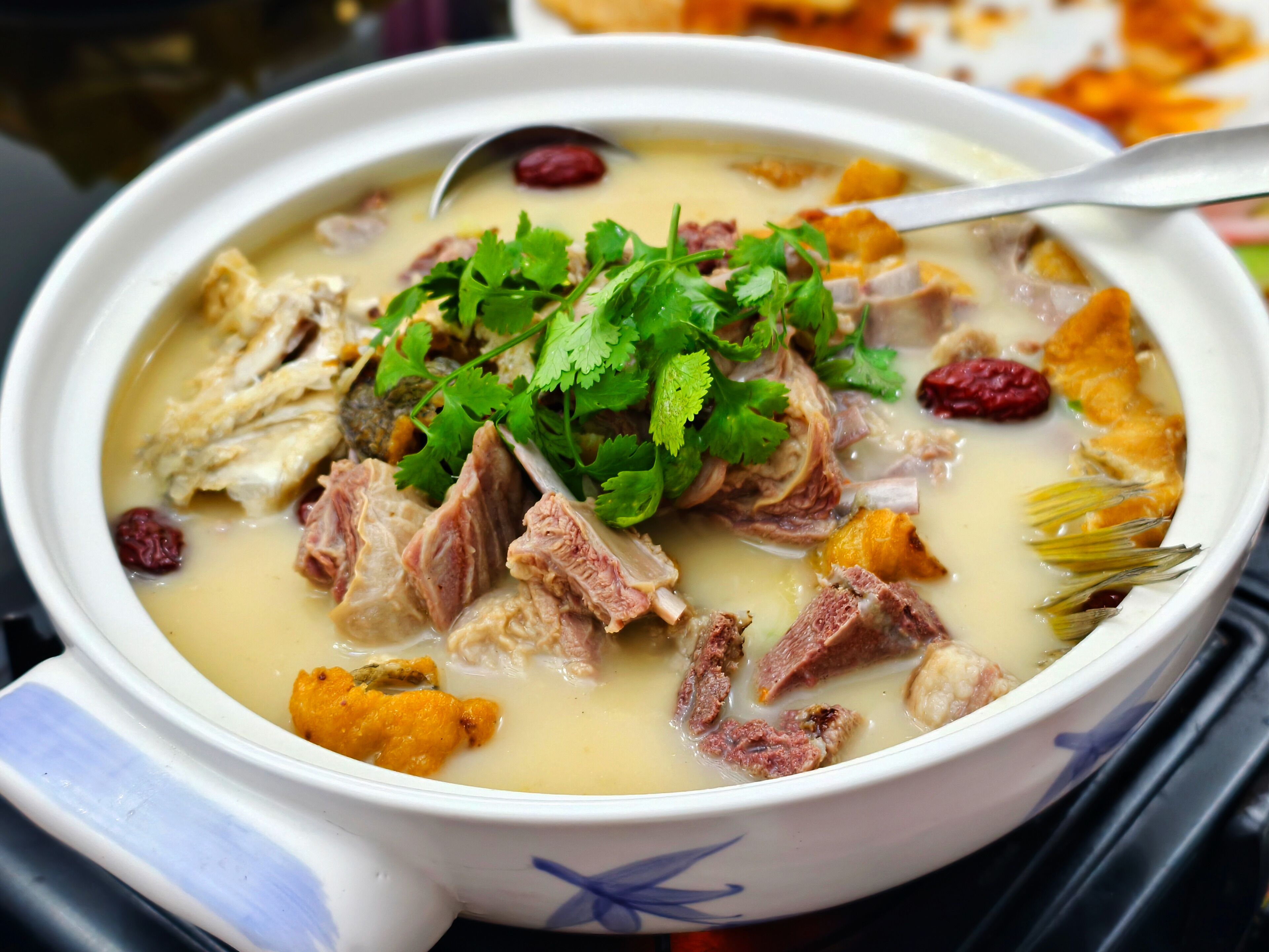 Un bol de soupe contenant de la viande et des légumes, garni de coriandre.