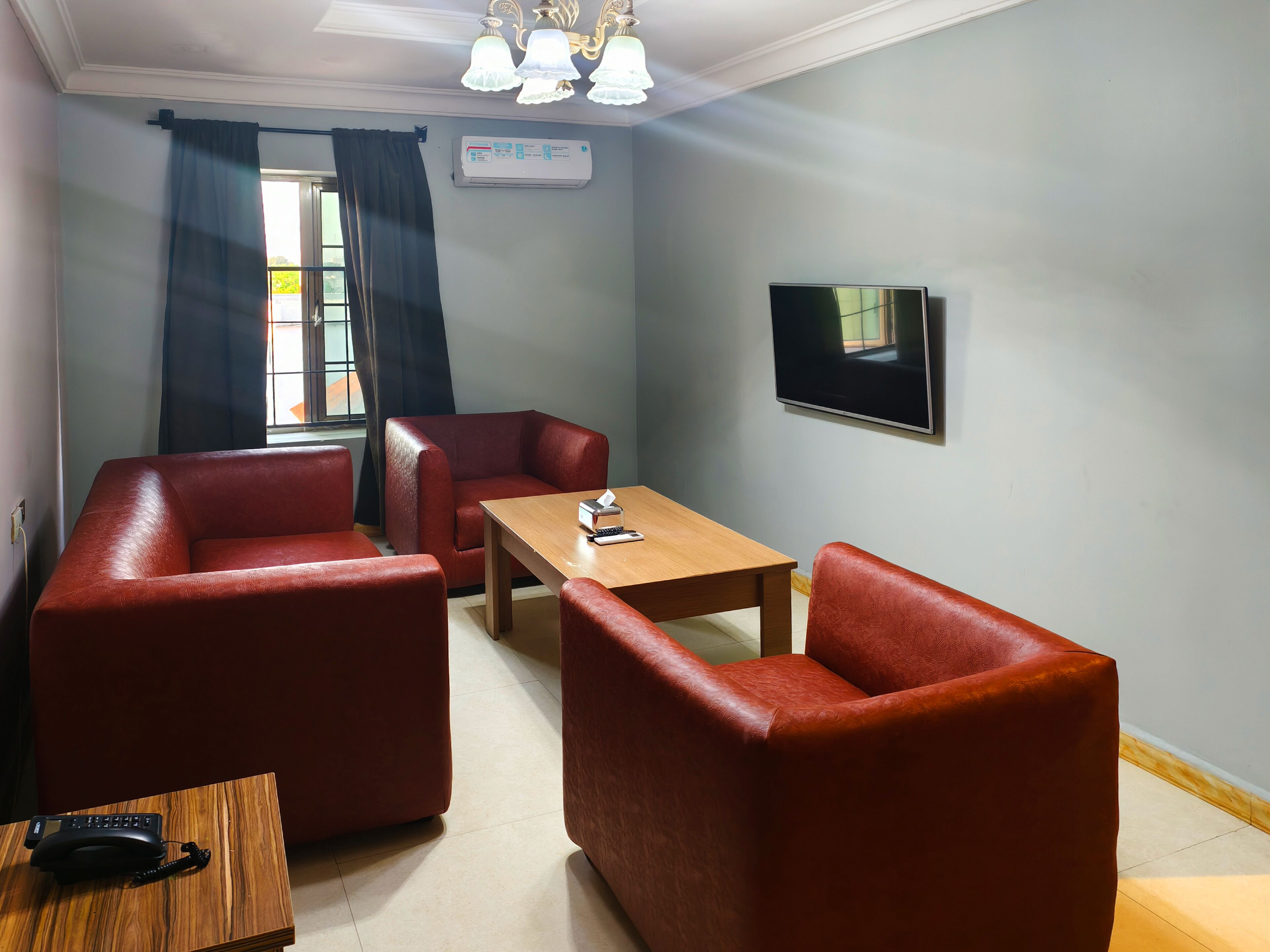 A room with a sofa, a wooden table, a TV, and a window with curtains.