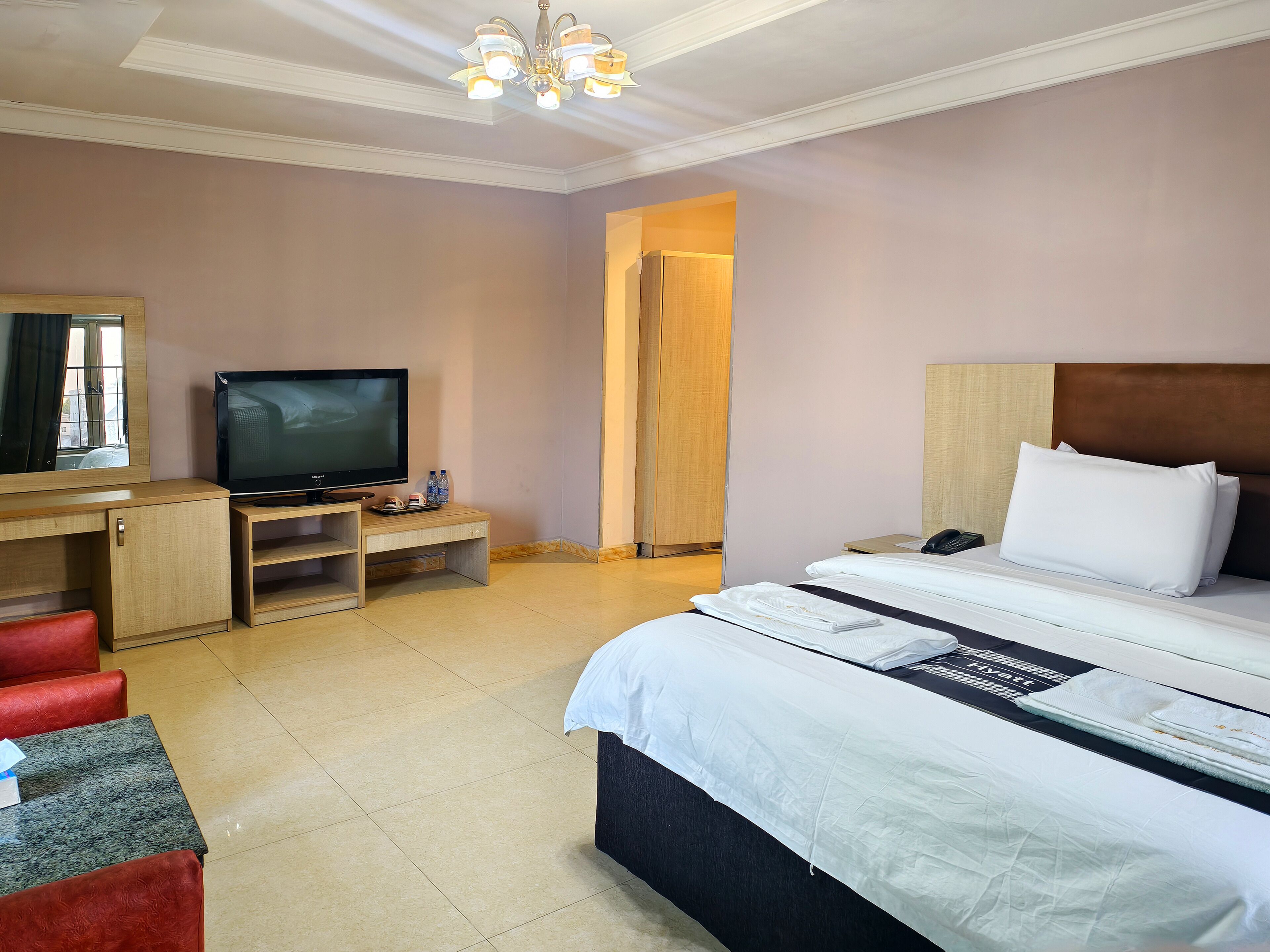 A hotel room with a bed, a TV, a desk, and a chair.