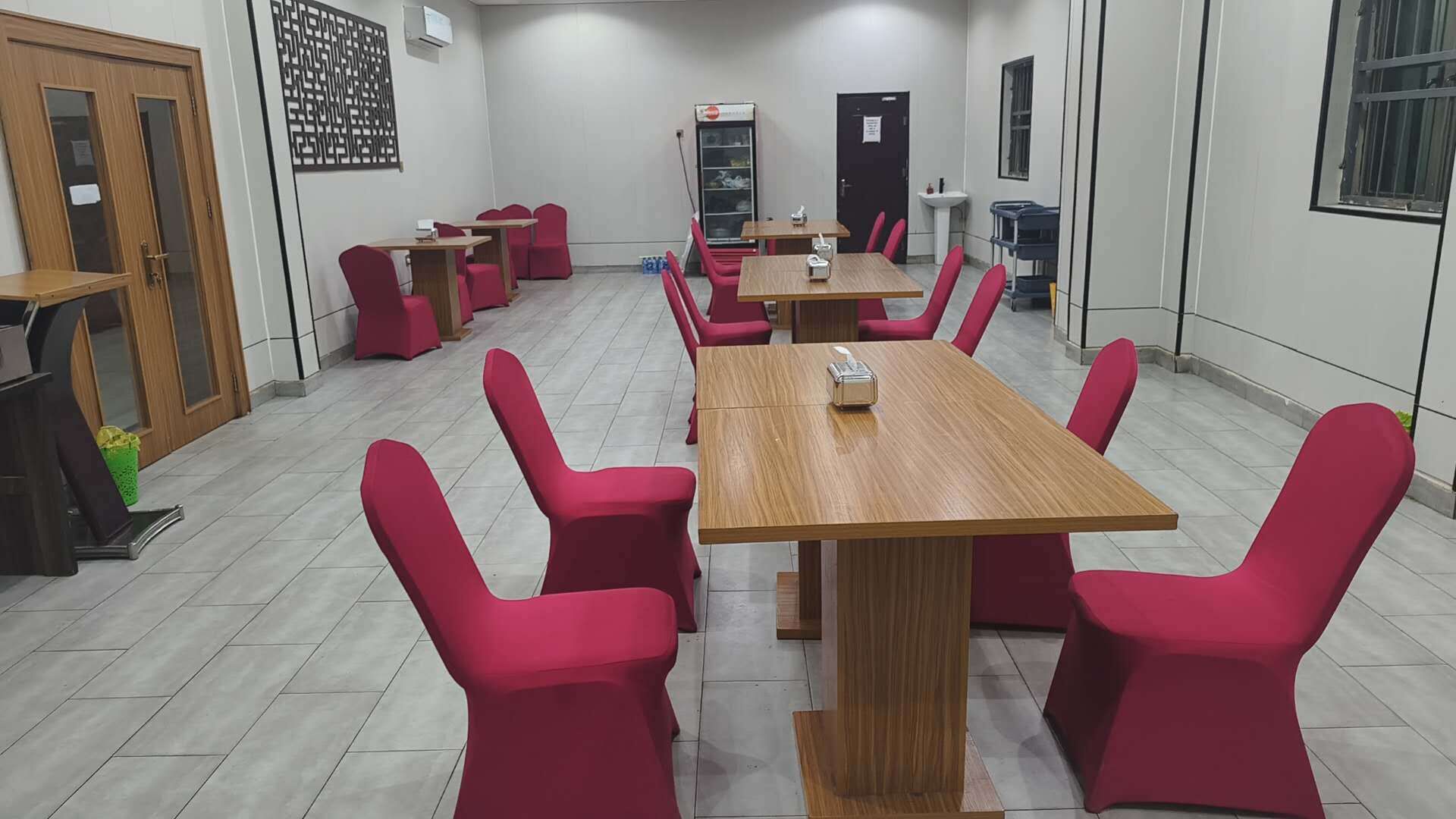 A conference room with red chairs and wooden tables, equipped with a projector and a whiteboard.