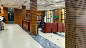 A hotel lobby with a modern design, featuring a long reception area, wooden pillars, and a seating area with leather sofas. - Jun Yue No. 9 Hotel  (Kano)