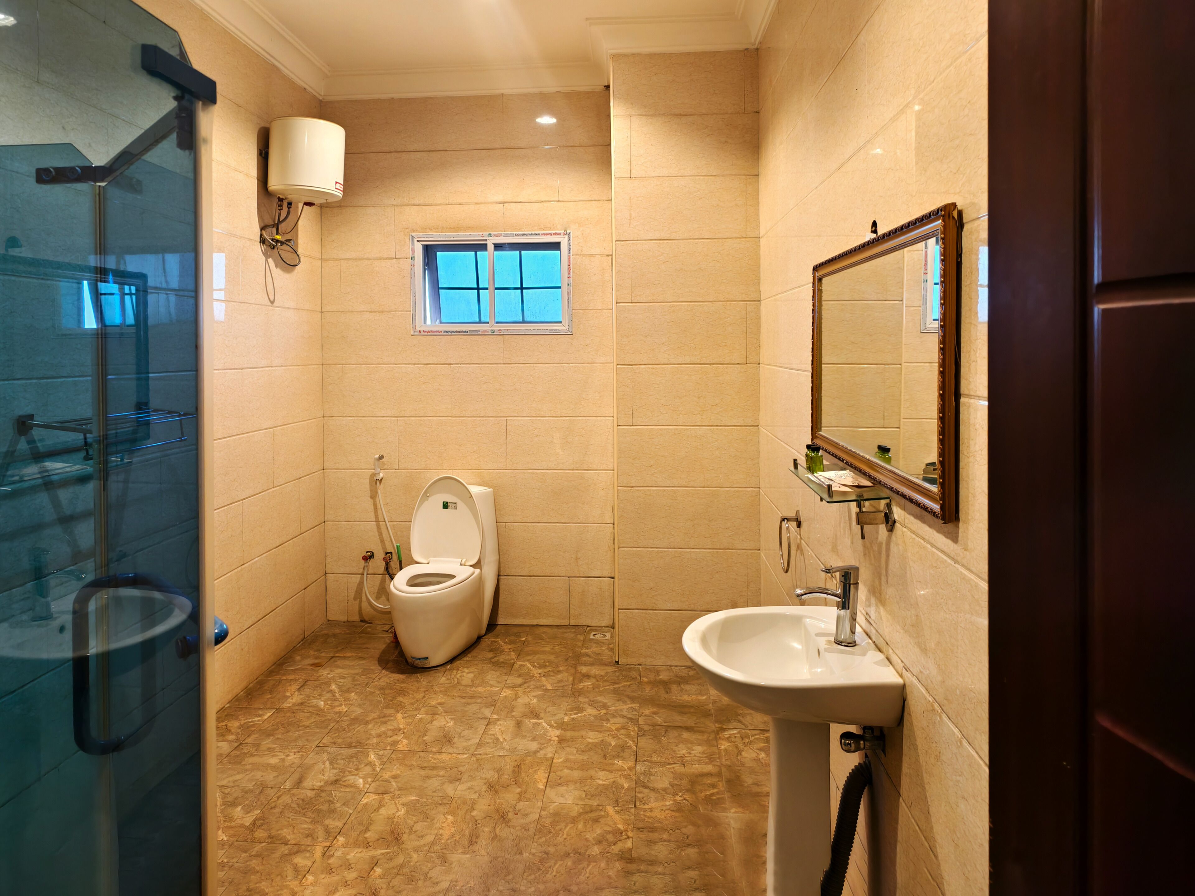 A bathroom with a toilet, sink, and glass shower enclosure.
