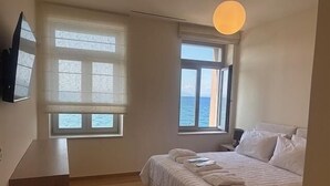 Une chambre à coucher avec un lit, un bureau et une fenêtre donnant sur la mer.