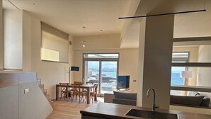 Une cuisine moderne avec un coin repas, un téléviseur et une vue sur la mer.