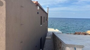 Ein schmaler Pfad, der zu einer Steinmauer mit Blick auf das Meer führt.