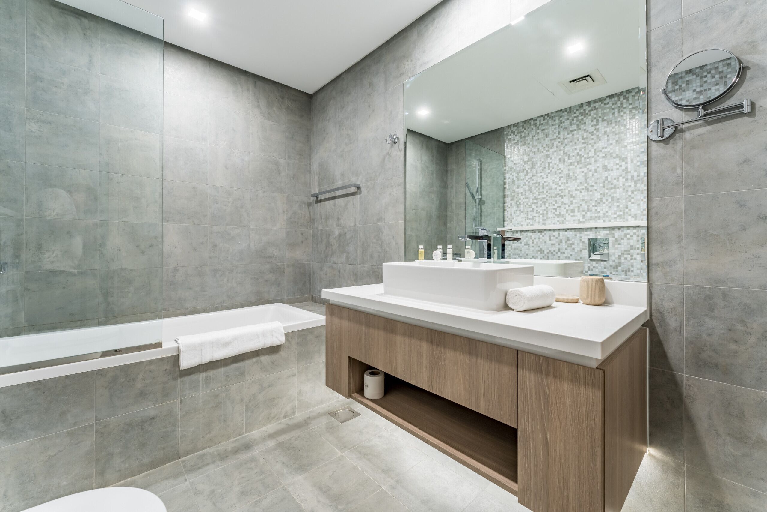 Un bagno moderno con uno specchio grande, una vasca da bagno e un lavabo con mobile.