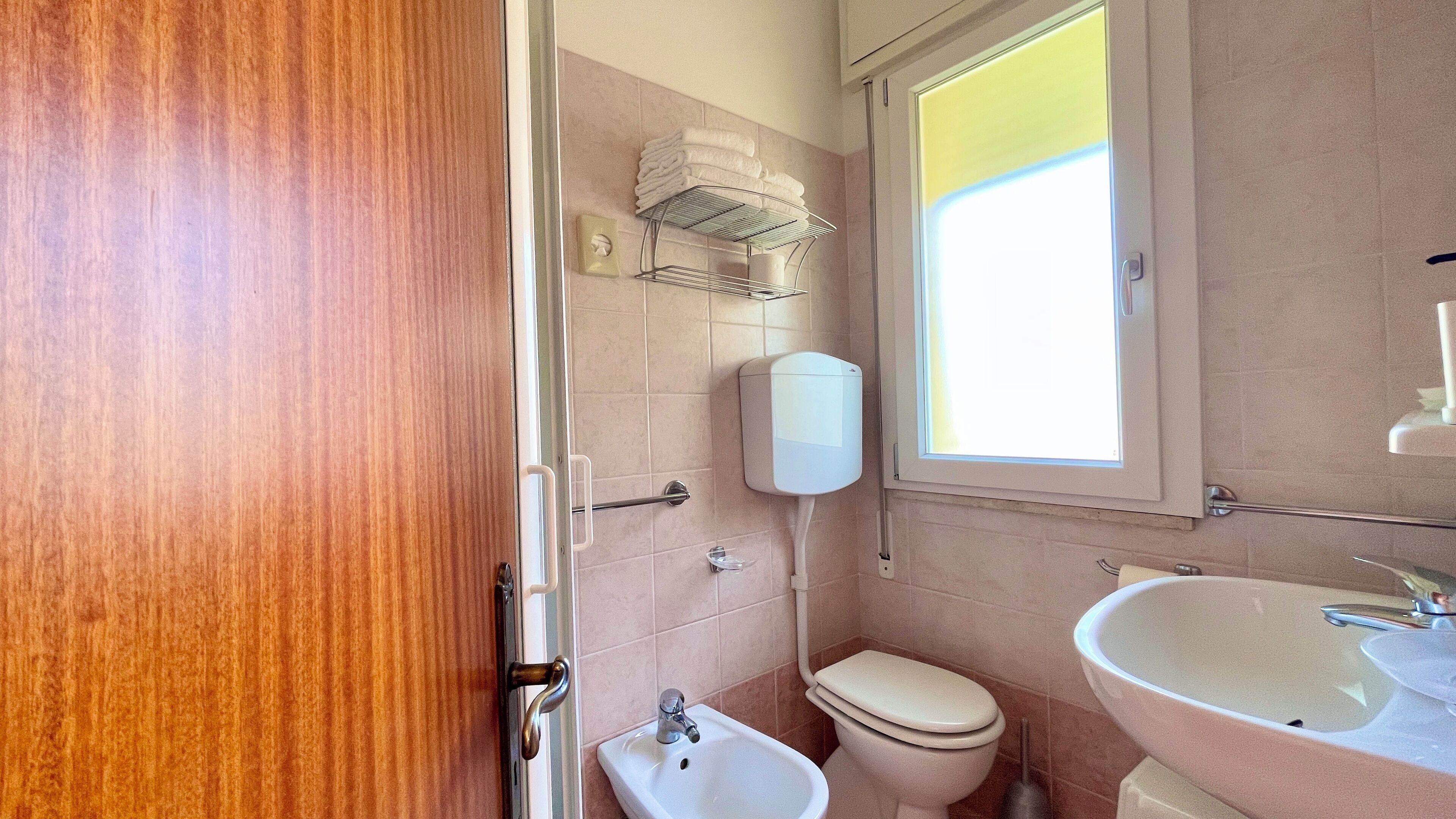 Une petite salle de bain comprenant des toilettes, un bidet, un lavabo et un porte-serviettes.
