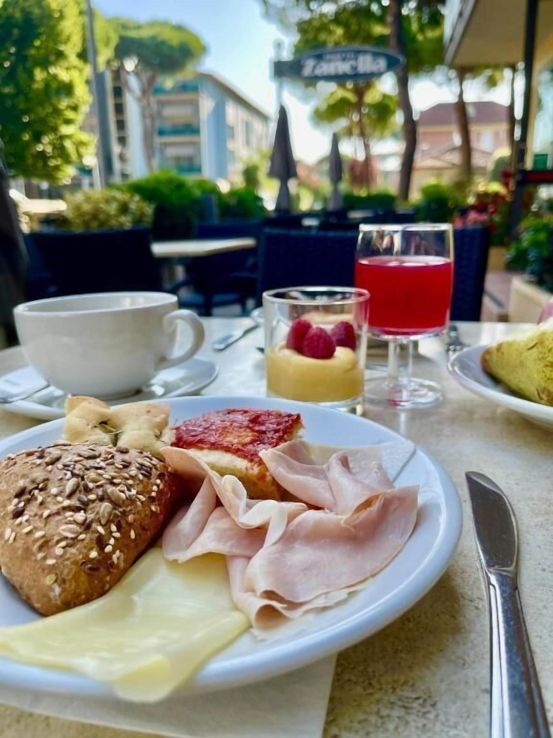 Un desayuno con un plato de comida, una taza y un vaso de jugo rojo.
