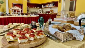 Une table de buffet proposant une variété de pains, de viennoiseries et de condiments.