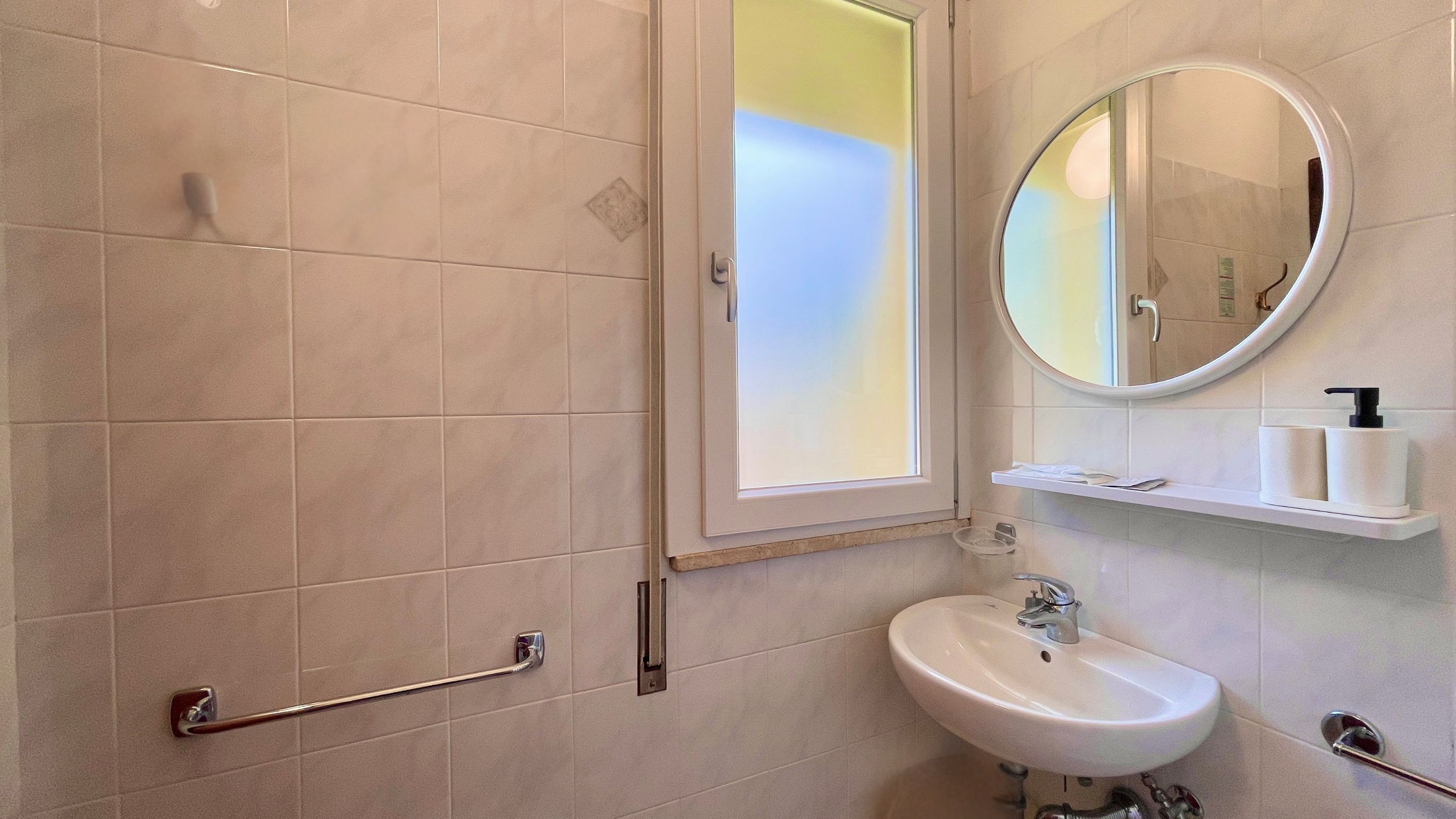 Un baño moderno con ducha, lavabo, espejo y ventana.