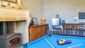 Una mesa de billar con bolas, una chimenea, un televisor y una zona de bar con sillas.