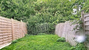 A backyard with a wooden fence, a grassy area, and a bench. - The garden of Gavrelle (Gavrelle)