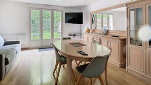 A modern living room with a dining area, large windows, and a kitchen with a TV. - The garden of Gavrelle (Gavrelle)