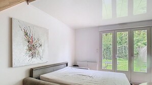 A bedroom with a bed, a bench, a chair, a desk, and a window with a view of greenery. - The garden of Gavrelle (Gavrelle)