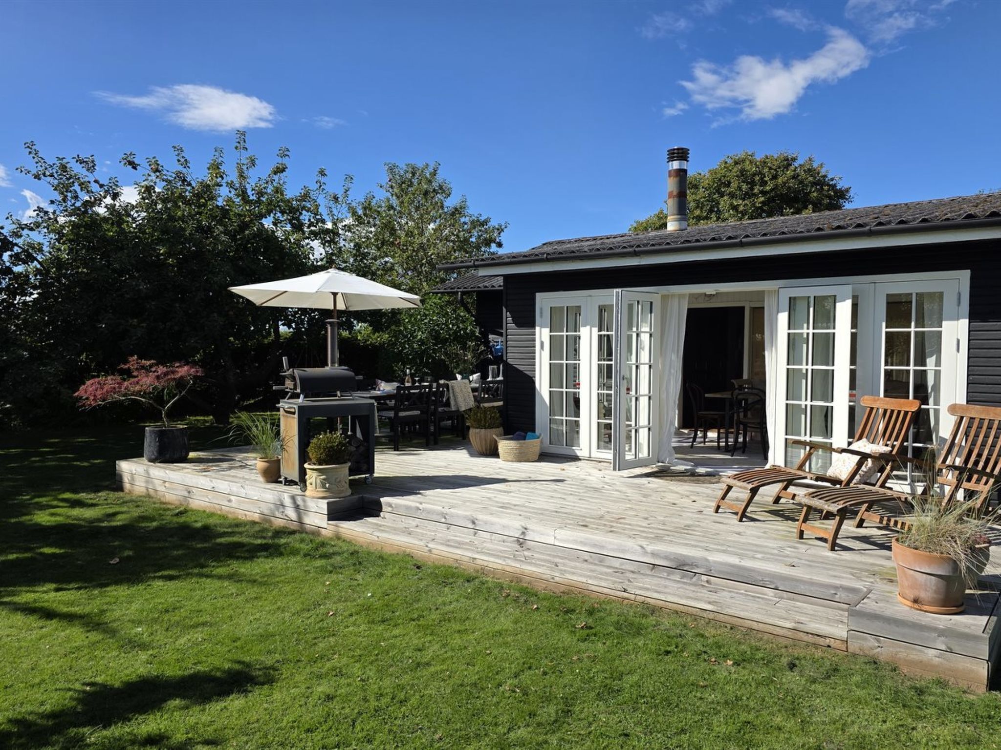 Une terrasse avec des meubles d’extérieur, un barbecue et un espace salon abrité.
