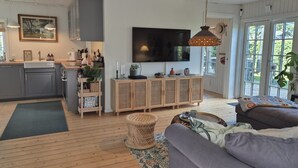 Un soggiorno moderno con un divano grigio, una televisione e un tavolino in vimini.