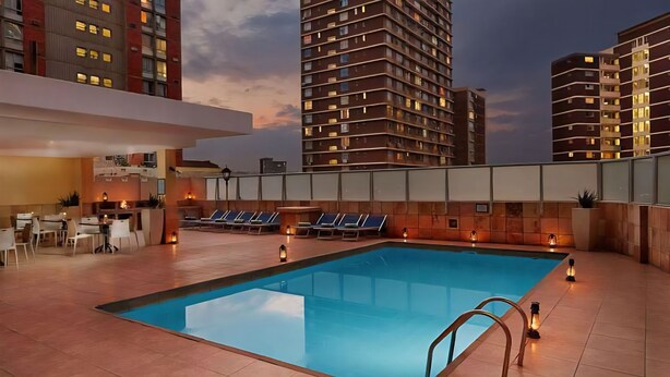 A rooftop pool area with lounge chairs and a bar, surrounded by high-rise buildings. - Modern Ocean View 6 Sleeper King Suite with Wi-Fi, Underground Parking (Durban)