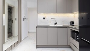 Una cocina moderna con encimera de mármol, pileta integrada y refrigerador negro.