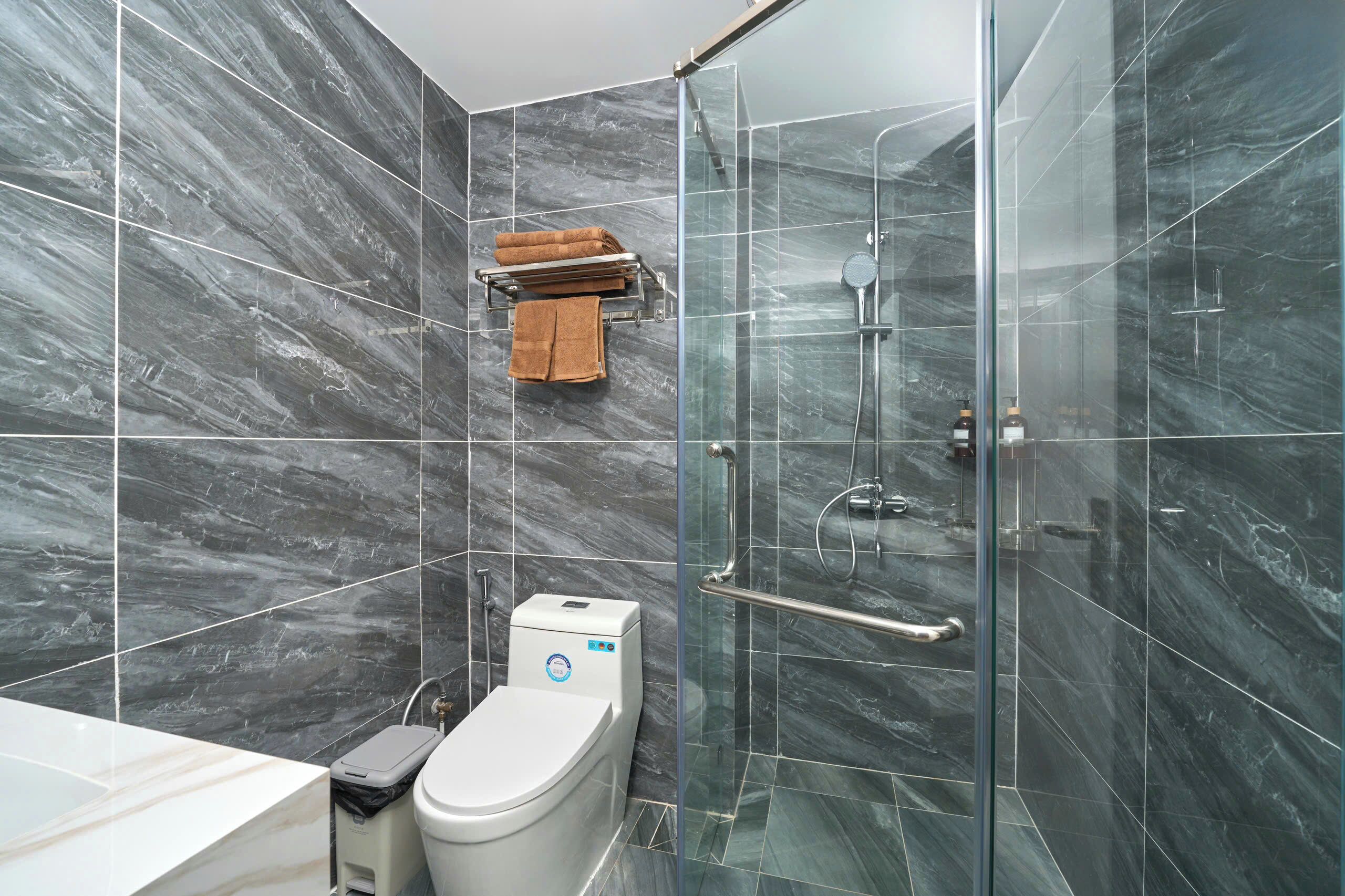 Un baño moderno con cabina de ducha de vidrio, inodoro y toallero.