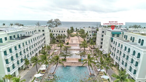 A hotel with a pool surrounded by palm trees and a view of the ocean. - Lumiere Boutique Phu Quoc Hotel (Phu Quoc)